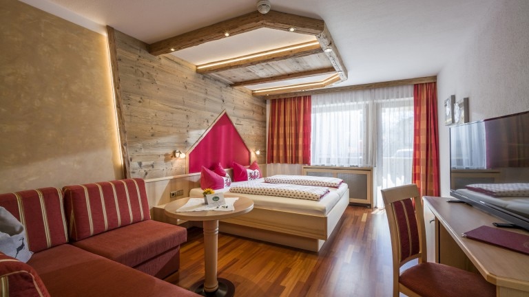 Kamer met tweepersoonsbed, bank en bureau.