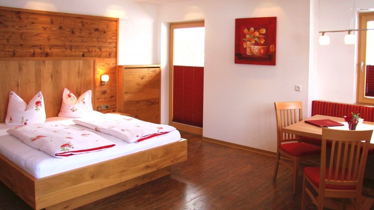 Kamer met een tweepersoonsbed, een tafel met stoelen en een bank.