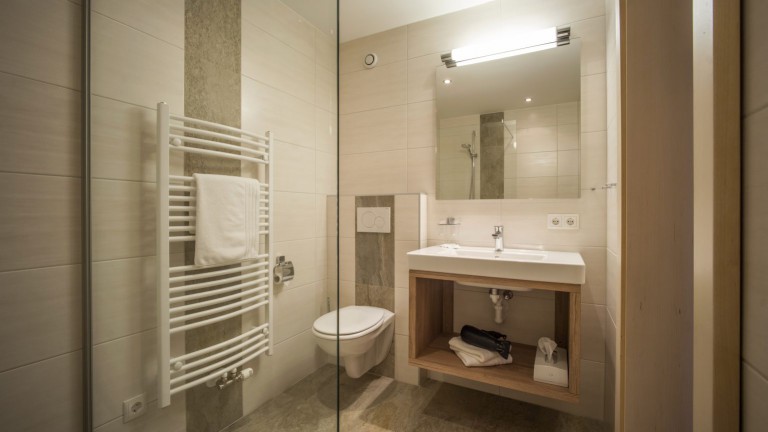 Badkamer met toilet, wasbak, spiegel en radiator.