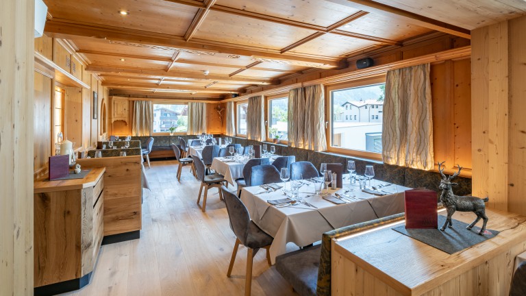 Restaurant van Hotel Alpina met bedekte tafels, zitbanken en stoelen.