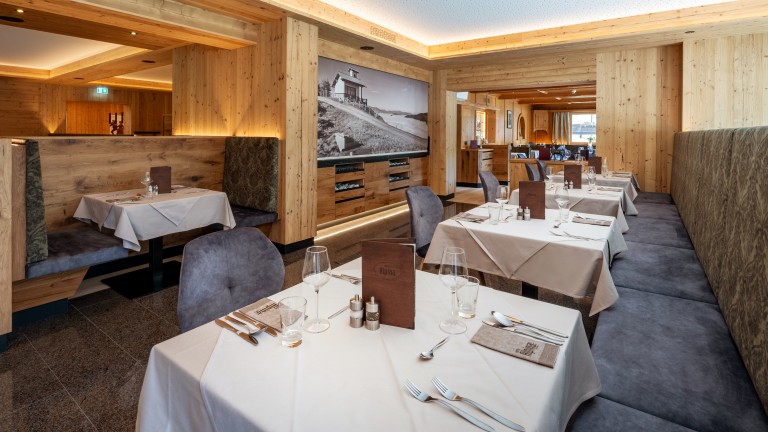 Restaurant van Hotel Alpina met gedekte tafels, zitbanken, stoelen en een nisje.