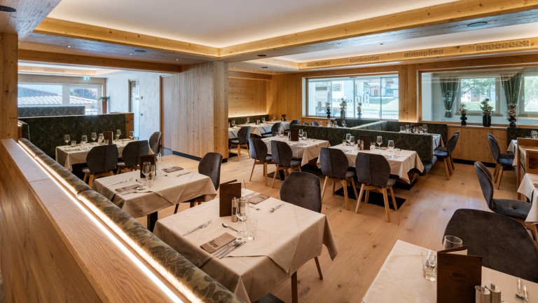 Restaurant van Hotel Alpina met gedekte tafels, stoelen en zitbanken.