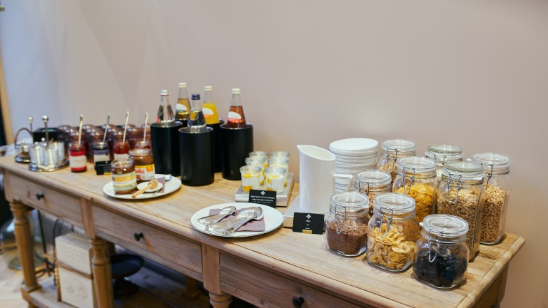 Ontbijtbuffet tafel met ontbijtgranen, zoet beleg en sappen.