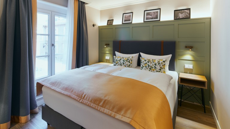 Standaard kamer orange met kingsize bed en ramen links.