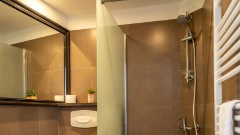 Badezimmer mit großem Spiegel und begehbarer Dusche.