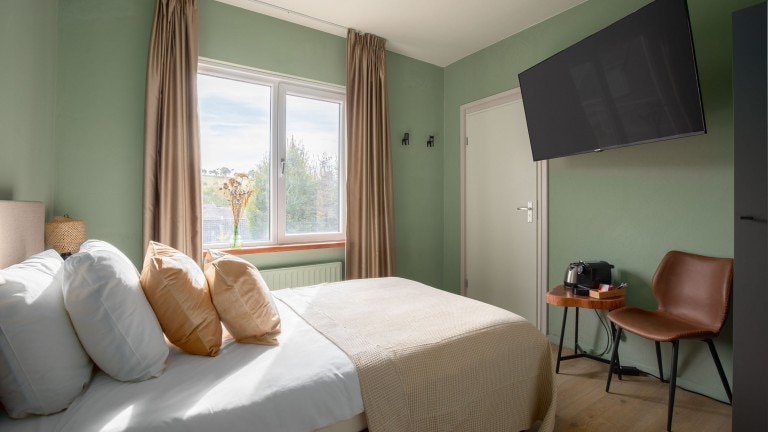 Eenpersoonsbed, televisie en zitje.