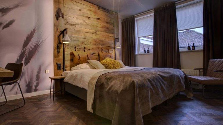 Hotelzimmer mit zwei Betten, einem Sitz und einer Holzrückwand.