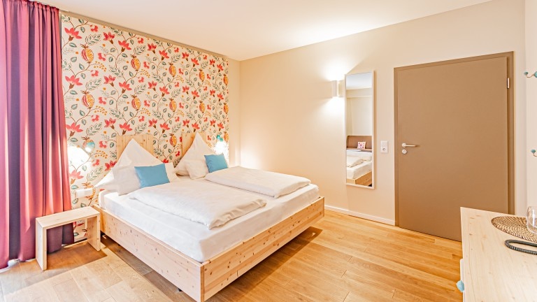 Hotelzimmer mit zwei Betten, Blumentapete und einem Nachttisch.