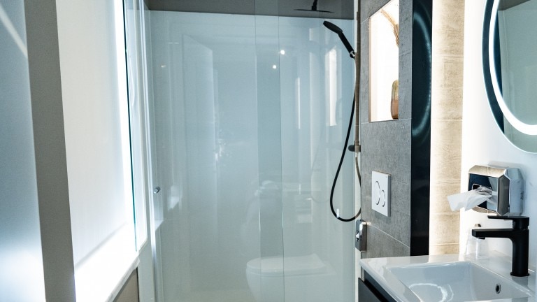 Badkamer met een glazen wand, wastafel en spiegel.